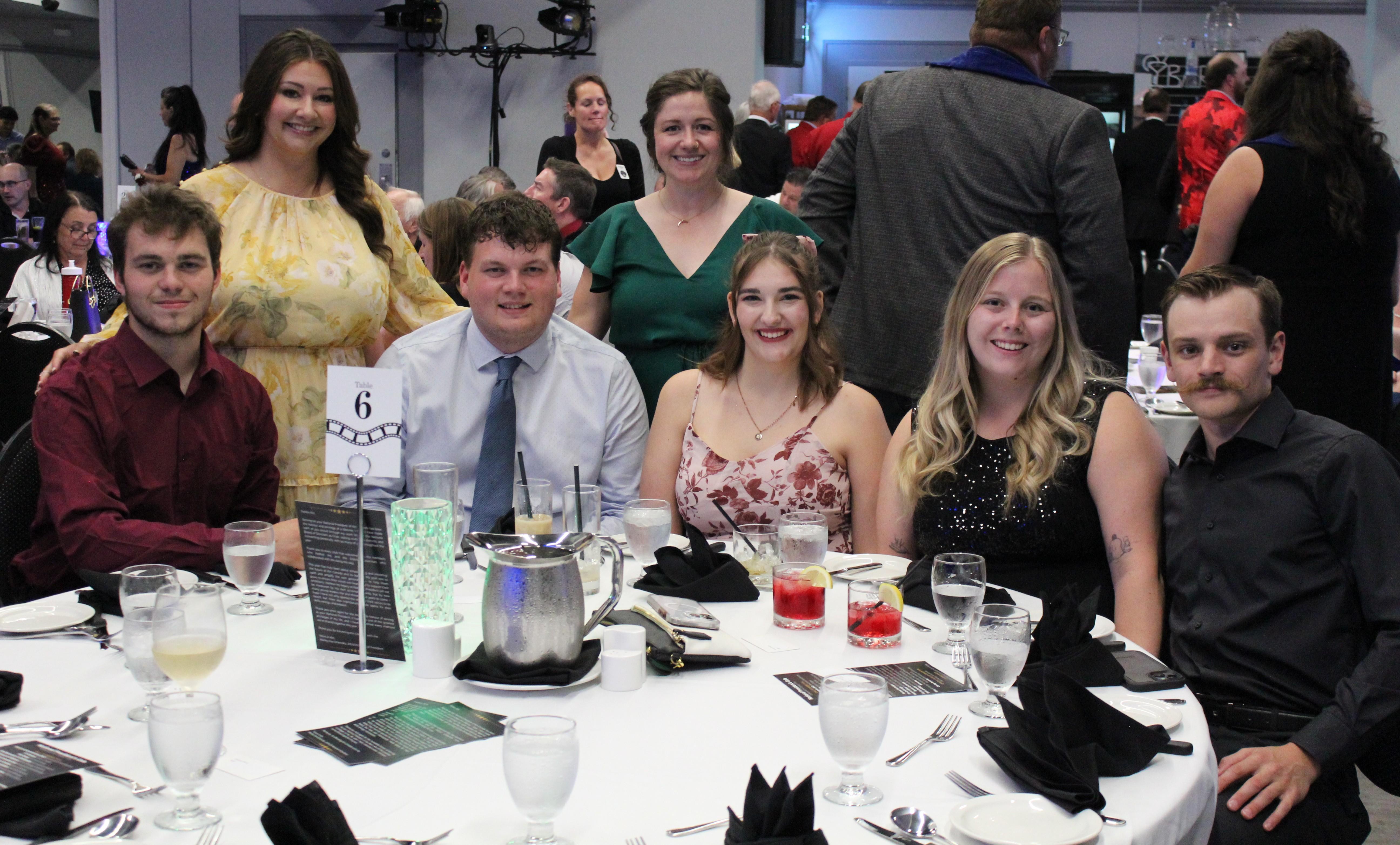 Picture of a group of people sitting and standing at a table at a convention